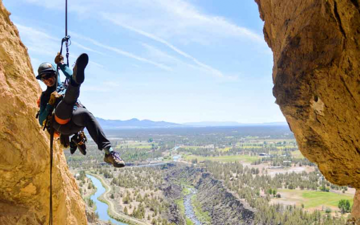 a rock climber is suspended in the air between two rock walls by a rope and harness